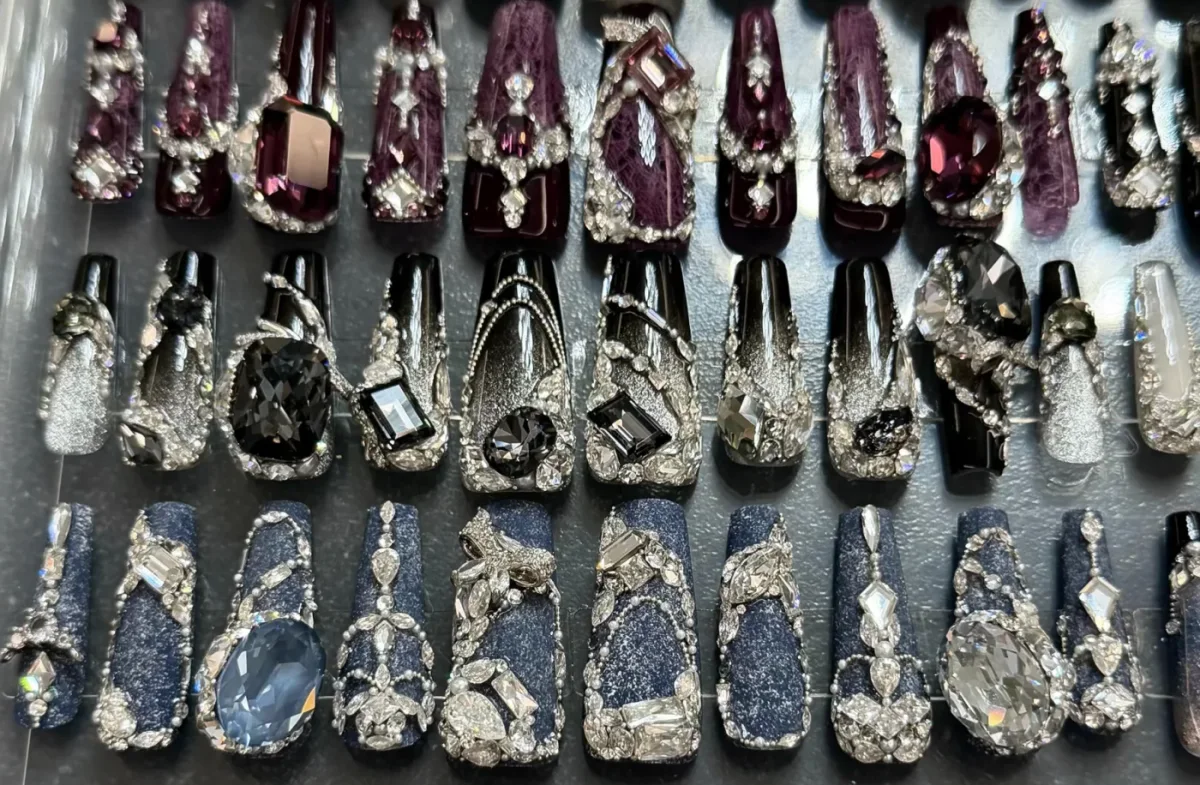 Purple, black and blue decorated press-on nail samples arranged in a display tray