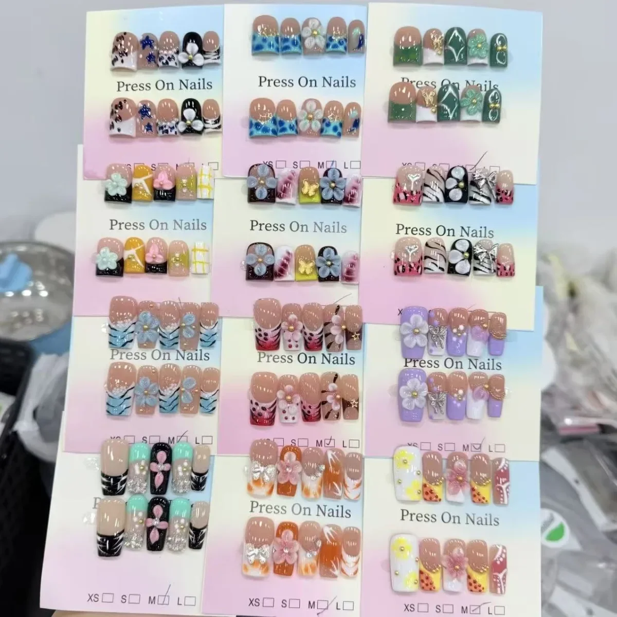 Press-on nail designs arranged on individual backing cards for product review